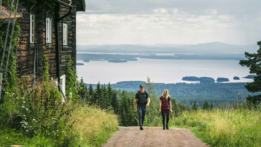 Kvinna och man vandrar med vy över Siljan