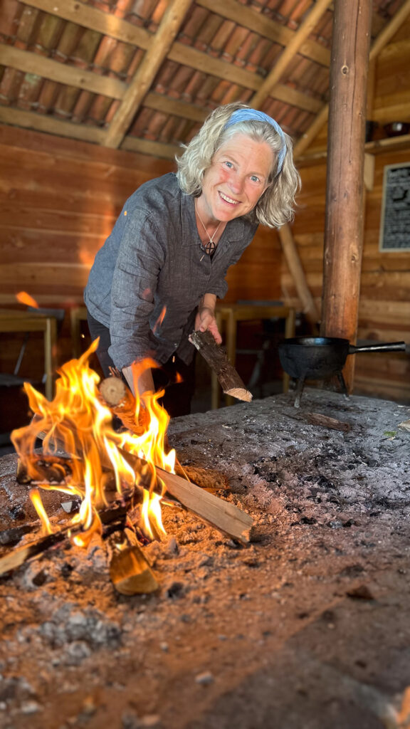 kvinna vid öppen eld i stuga